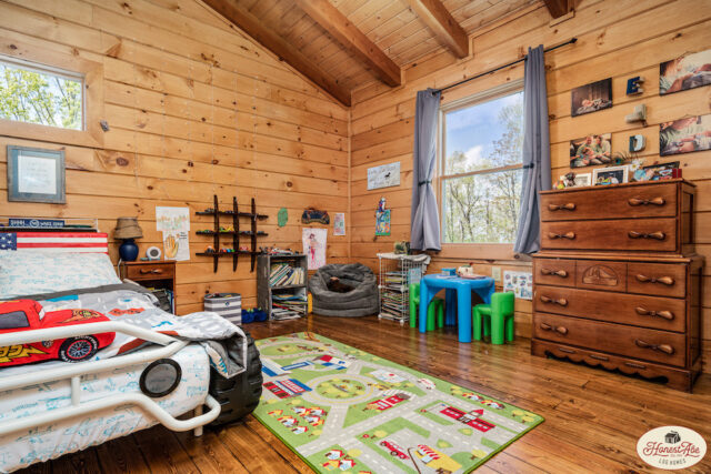 Photo of chlidren's bedroom in log home with wood walls and ceiling and matching wood floors