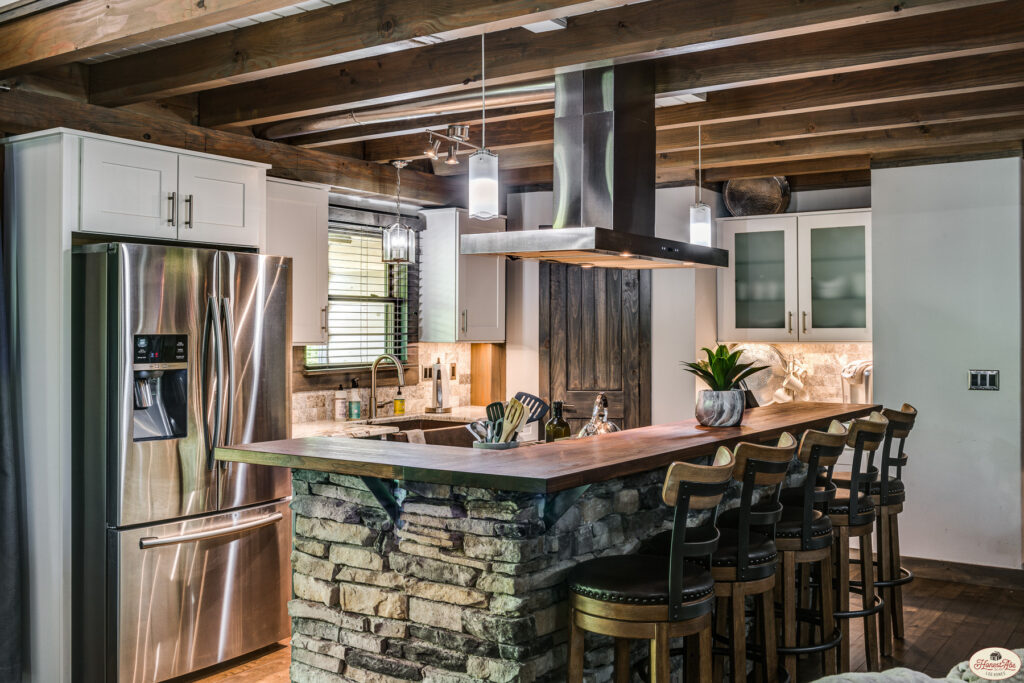 Photo of kitchen with stone island and wood support beams along with wood flooring.