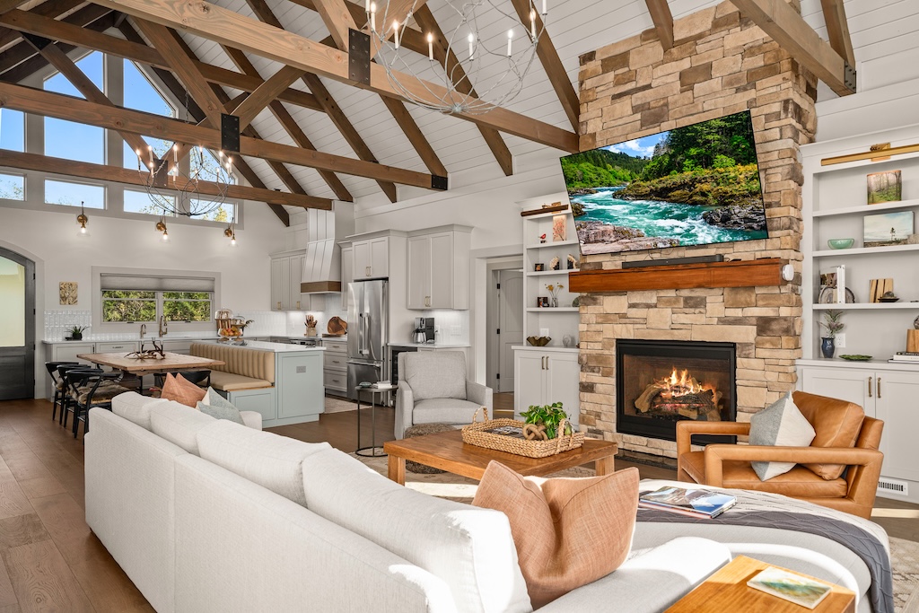 Photo of timber frame home with stone and wood exterior and three car garage bay attached to the home by an enclosed breezeway. Photo taken at sunset